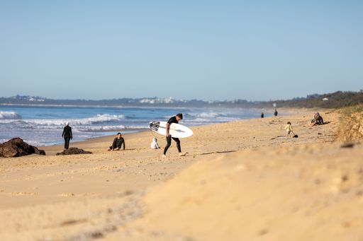 A surfer holding the surfboard on the Yaroomba beach on the coast of Queensland Australia