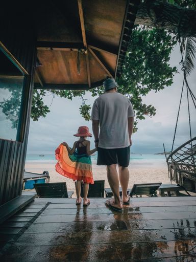 Father and little daughter holding hands at the beach resort.