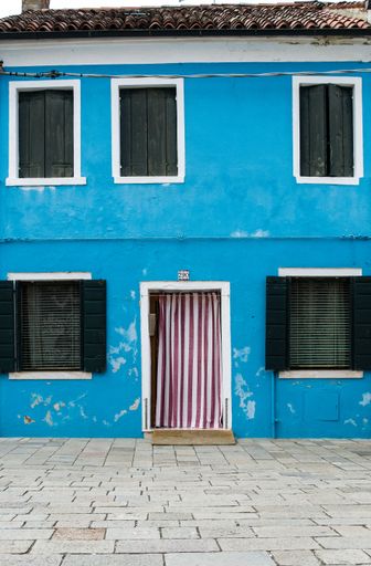 A vertical shot of a blue two-story building with a cloth door