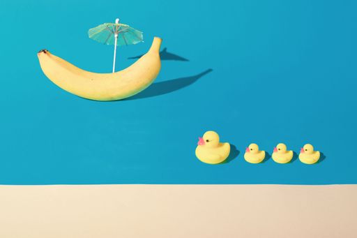 Toy Ducks and banana boat with umbrella, modern background. Beach. Minimal abstract concept