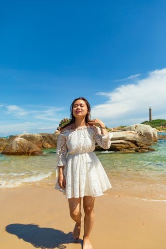 A vertical shot of a young lady on the seashore on a cloudy day