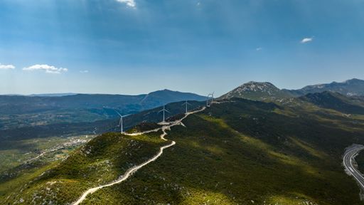 Aerial view around wind power turbines, on top of sunny mountains in eastern Europe