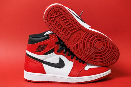 A Pair of Air Jordan 1 Sneakers from the side and bottom isolated on the red background