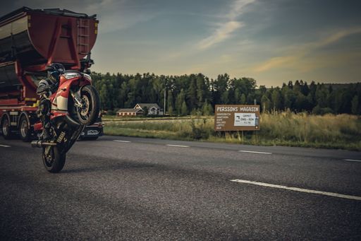 A biker riding an Yamaha R1 on the back wheel on the road
