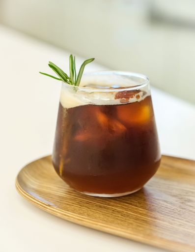 A vertical shot of a glass of iced coffee on a wooden tray