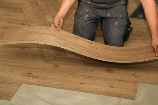 A worker installing new vinyl tile floor