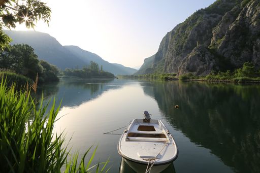 A beautiful view of a fishing boat on a lake surrounded by greenery and mountains in the early morning