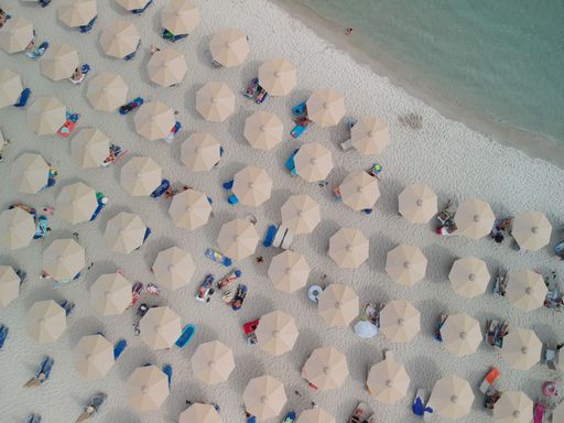 An aerial top view of people on the beautiful Makryammos beach with umbrellas in Thassos, Greece