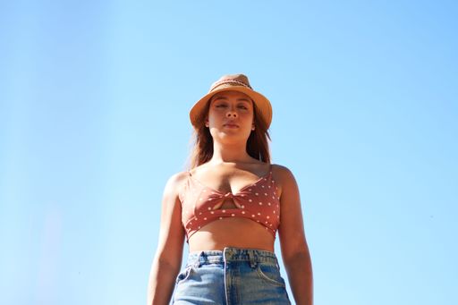 A beautiful young woman in a straw hat standing against blue sky background