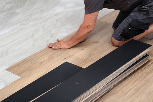 A worker installing new vinyl tile floor