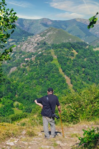 A vertical shot of a man standing and looking at a beautiful mountain range