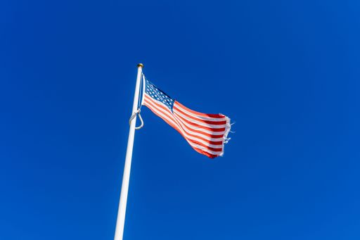 A low angle of an American Flag under a clear blue sky