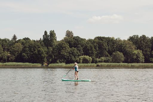 A adult female enjoys a recreational kayaking activity in a tranquil outdoor setting