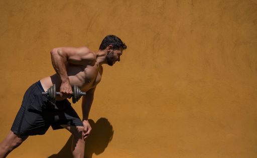 A male working out outdoors below harsh sun light