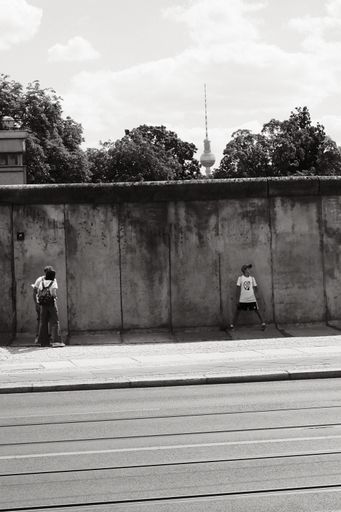 A vertical shot of people in front of the old Berlin Wall with Berlin TV Tower in Germany