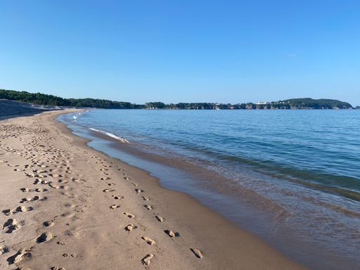 A beautiful view of a beach with footprints in the sand and sea waves under a clear sky
