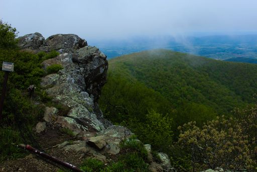 A view from high rocks to the mountains covered by green forests under the foggy sky in Shenandoah National Park