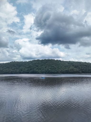 A vertical shot of the sea coast and green hill on a cloudy day