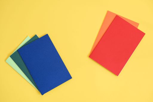 notebooks in different colors on bright yellow background from above