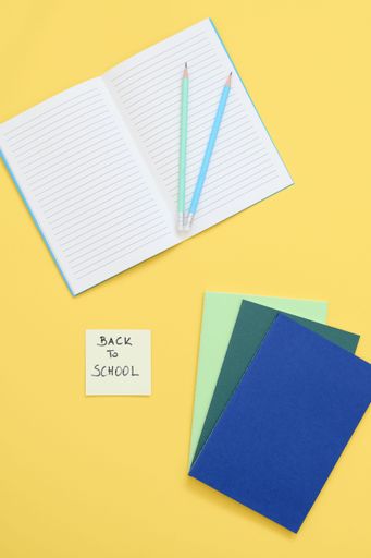 text with back to school note, notebook and pencil on yellow bac
