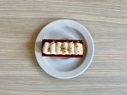 Top view of a Toffee cake with a whipped cream on a white plate on wooden table.