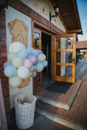 A vertical shot of a bunch of balloons on a bucket in front of a house
