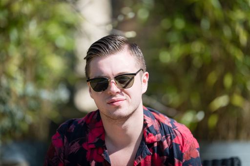A shallow shot of a caucasian male wearing black glasses with sunlight on his face