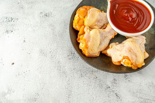 chicken drumstick and sauce, high angle top view