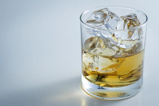 A closeup shot of a glass full of ice and some whiskey isolated on a white background