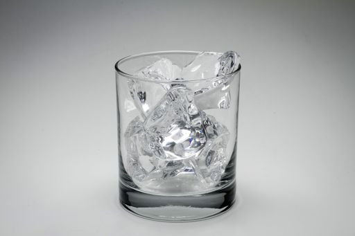 A closeup gray scale shot of a glass full of ice cubes isolated on a white background