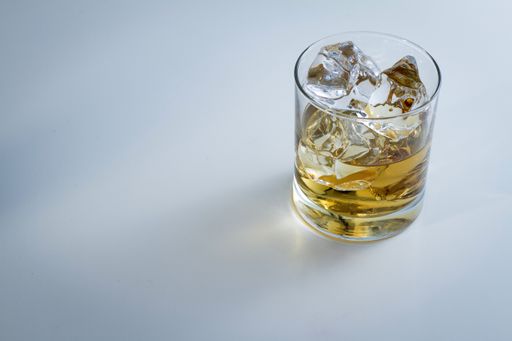 A high angle shot of a glass full of ice and some whiskey isolated on a white background
