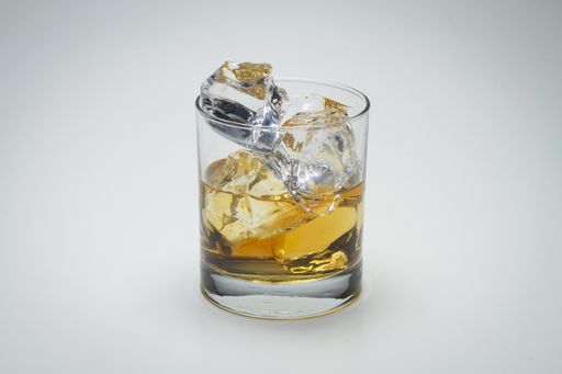 A closeup shot of a glass with whiskey and icecube on a white surface - great for a blog