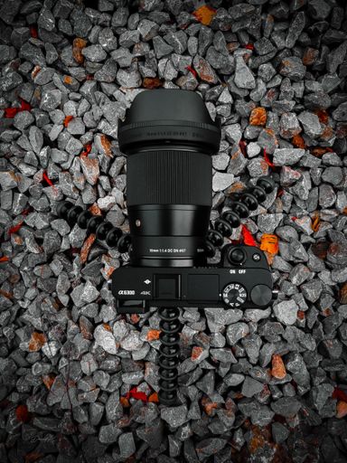 An vertical overhead shot of a DSLR camera on a tripod against gravel background