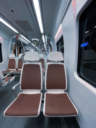 A vertical shot of the brown white seats in the interior of a train wagon