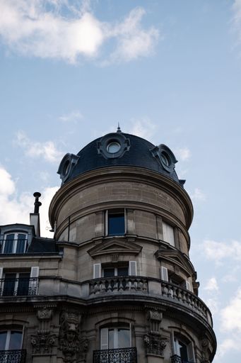 A low angle shot of a classical Haussmannian apartment building with under blue sky in Paris, France