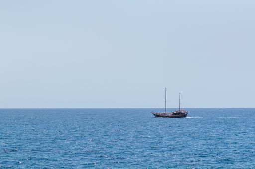 An artisanal fishing boat in the sea with blue sky on the horizon