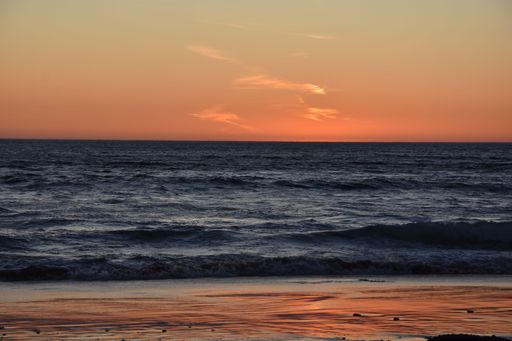A bright golden orange sunset sky over a seashore