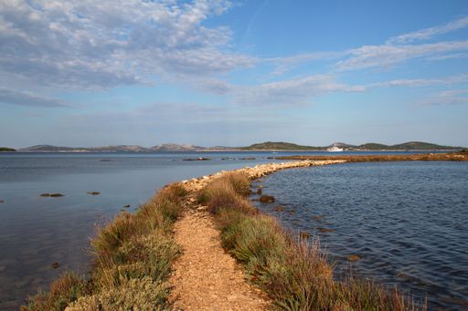 A sunny scenery of a narrow road going through the sea