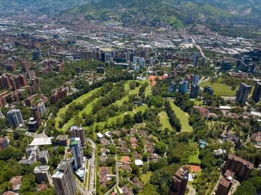 An aerial shot of a downtown El Poblado in Medellin, Colombia with green-covered hills on background