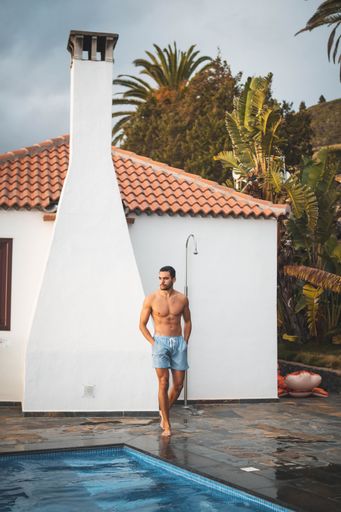 A vertical shot of an attractive guy walking on the edge of the pool