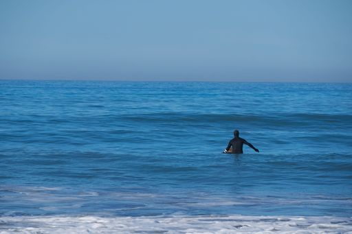 A closeup shot of a surfer swimming in the sea on a sunny day