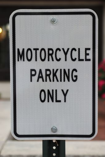 A selective focus shot of a motorcycle parking only sign on a street