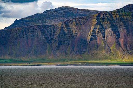 A summer view near Akranes, surrounded by dramatic clouds. A small patch of unmelted snow is visible.