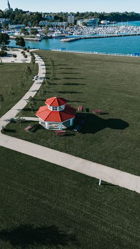 An aerial shot of a white gazebo with red roof at the coast