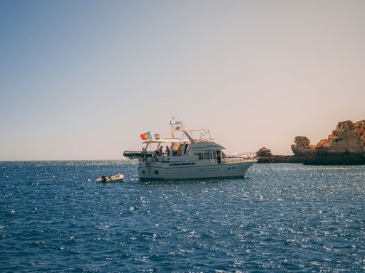 Different kinds of boats in front of Benagil caves and beach with tourists, Algarve, Portugal
