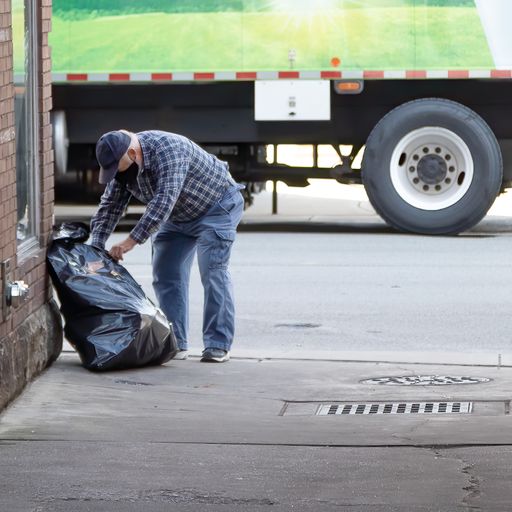 A closeup shot of a man wearing a mask looking through the trash