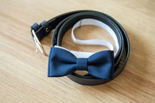 A closeup shot of a bow blue tie  on a leather belt on a wooden background