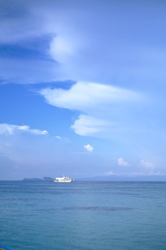 A vertical shot of a boat sailing on the Island of Ko Lipe, Thailand