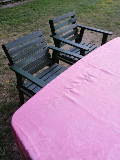 A vertical shot of pink tablecloth with roses on a table and chairs