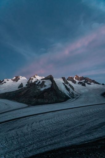 A vertical shot of the snowy rocky mountains under an evening sky in Fieschertal, Switzerland